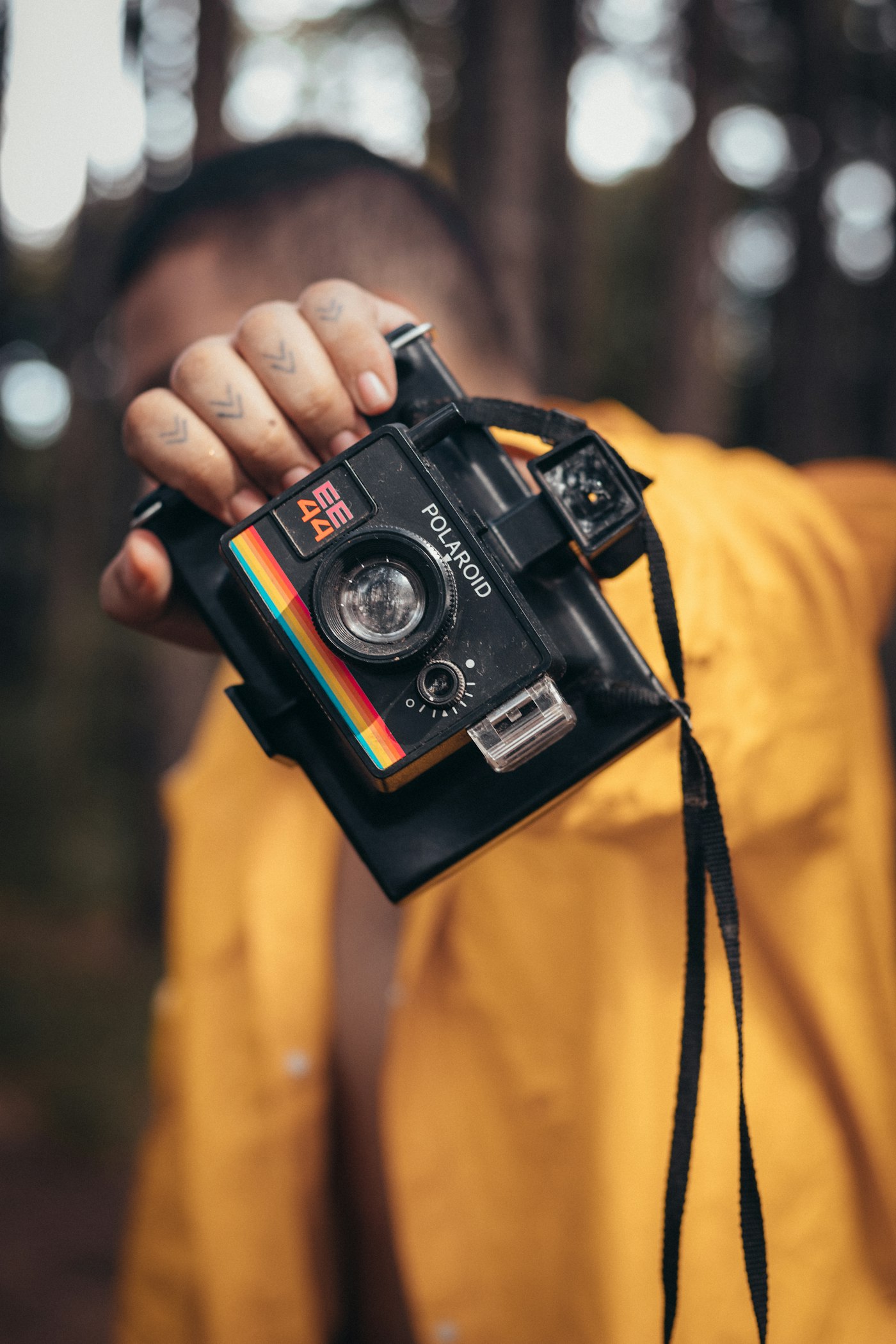 Person holding a rainbow-striped instant camera