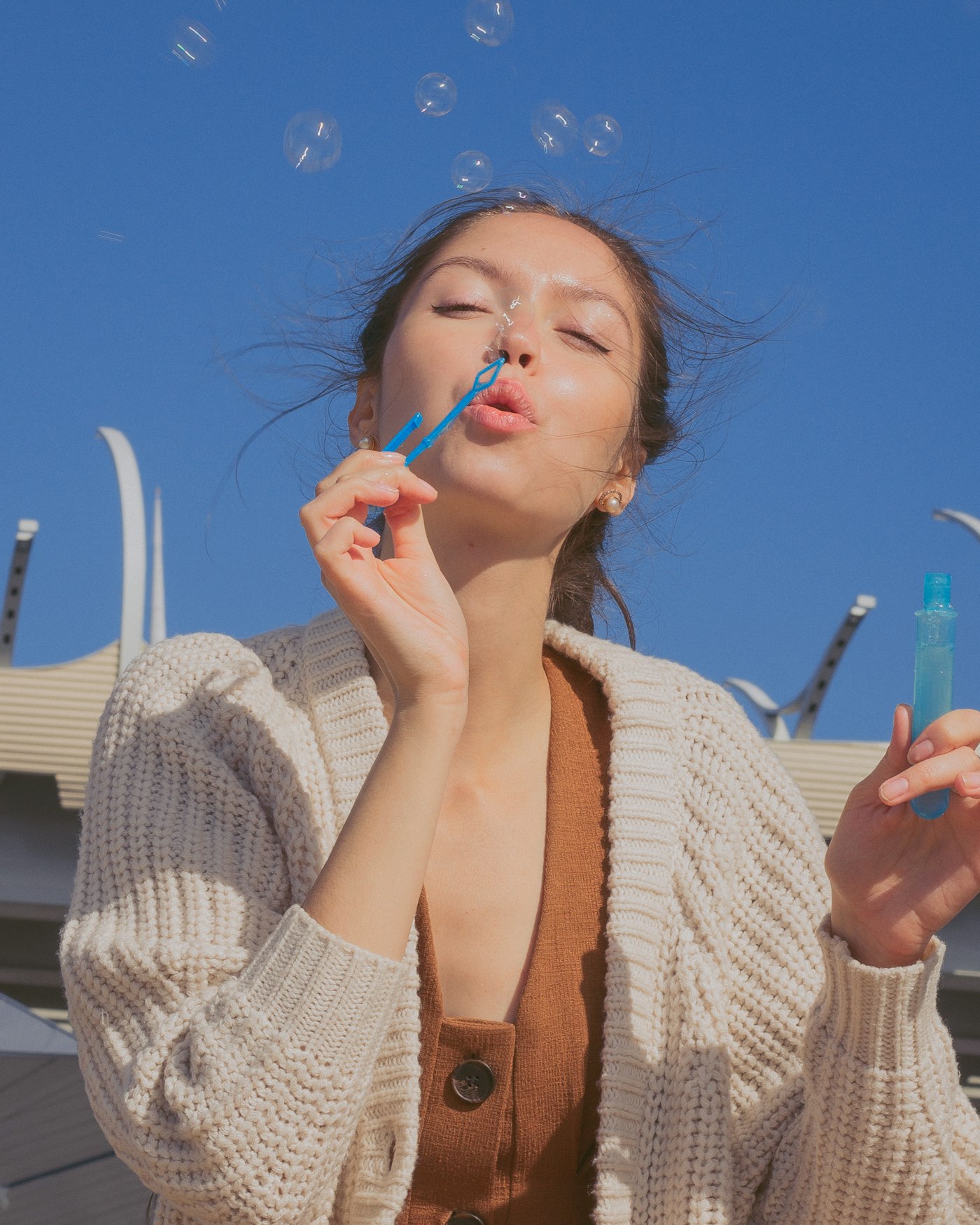 Woman blowing bubbles under a blue sky
