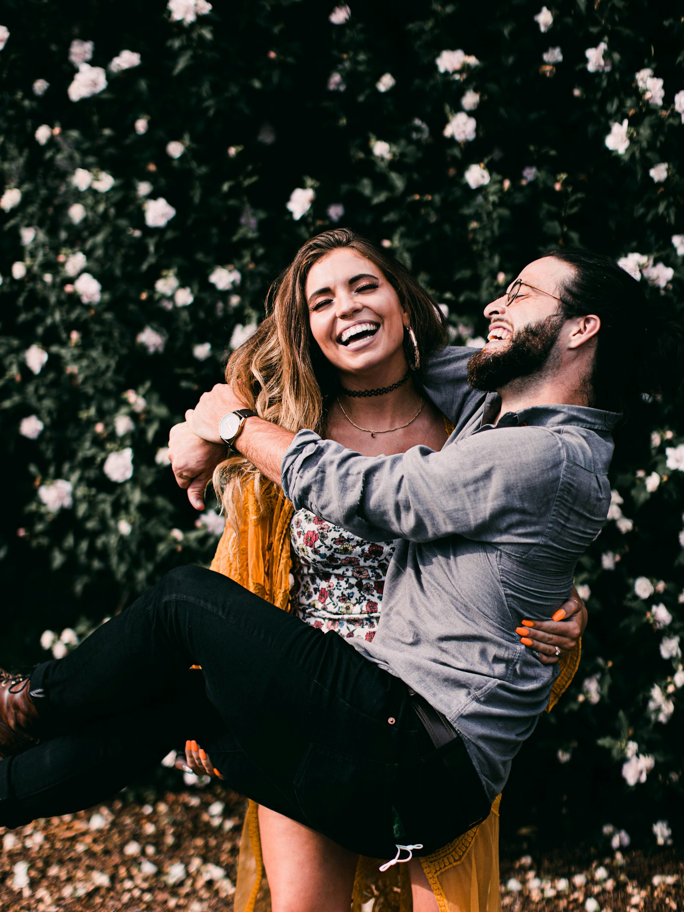 Couple laughing in front of a flowering bush