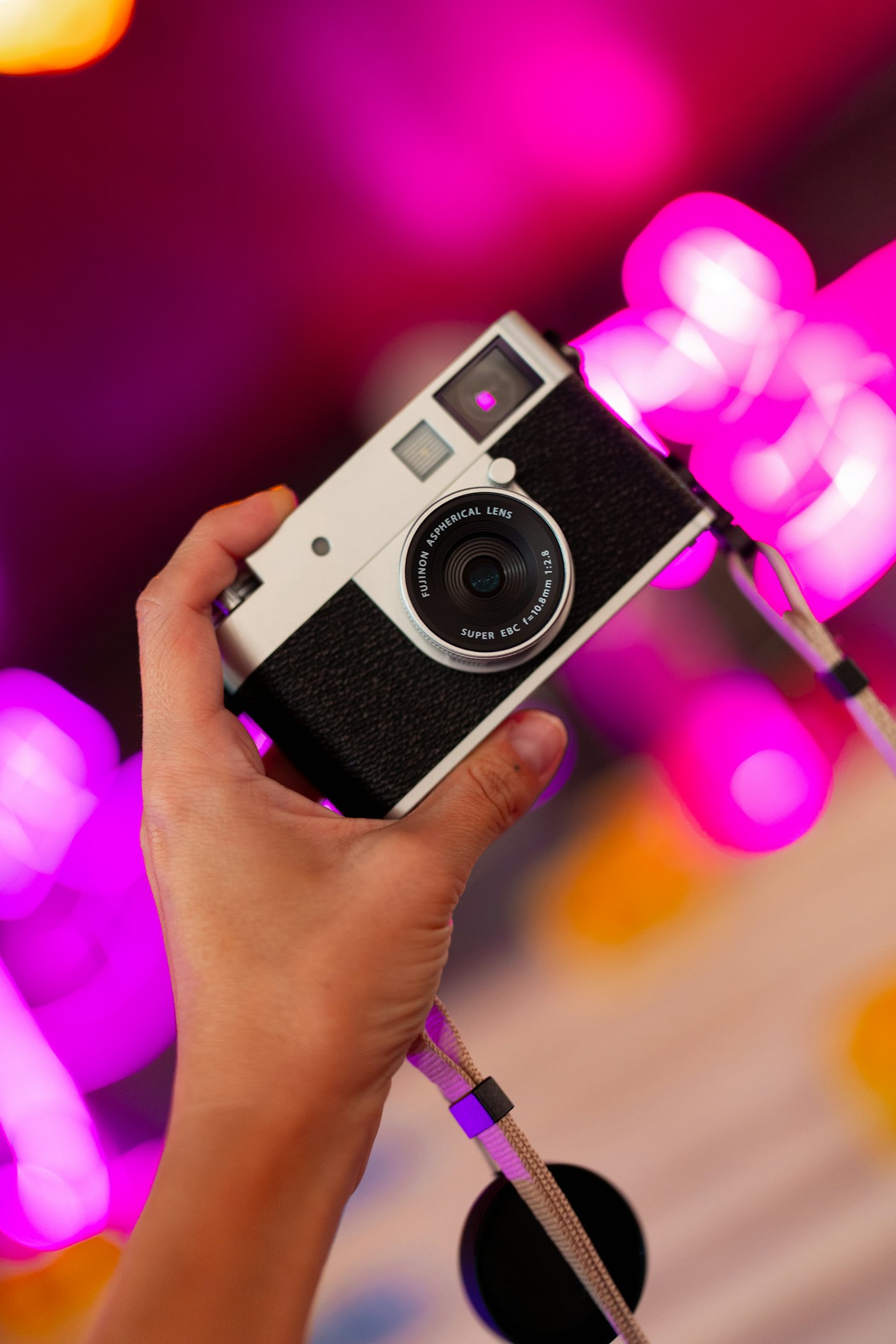 Hand holding a vintage camera against pink neon lights