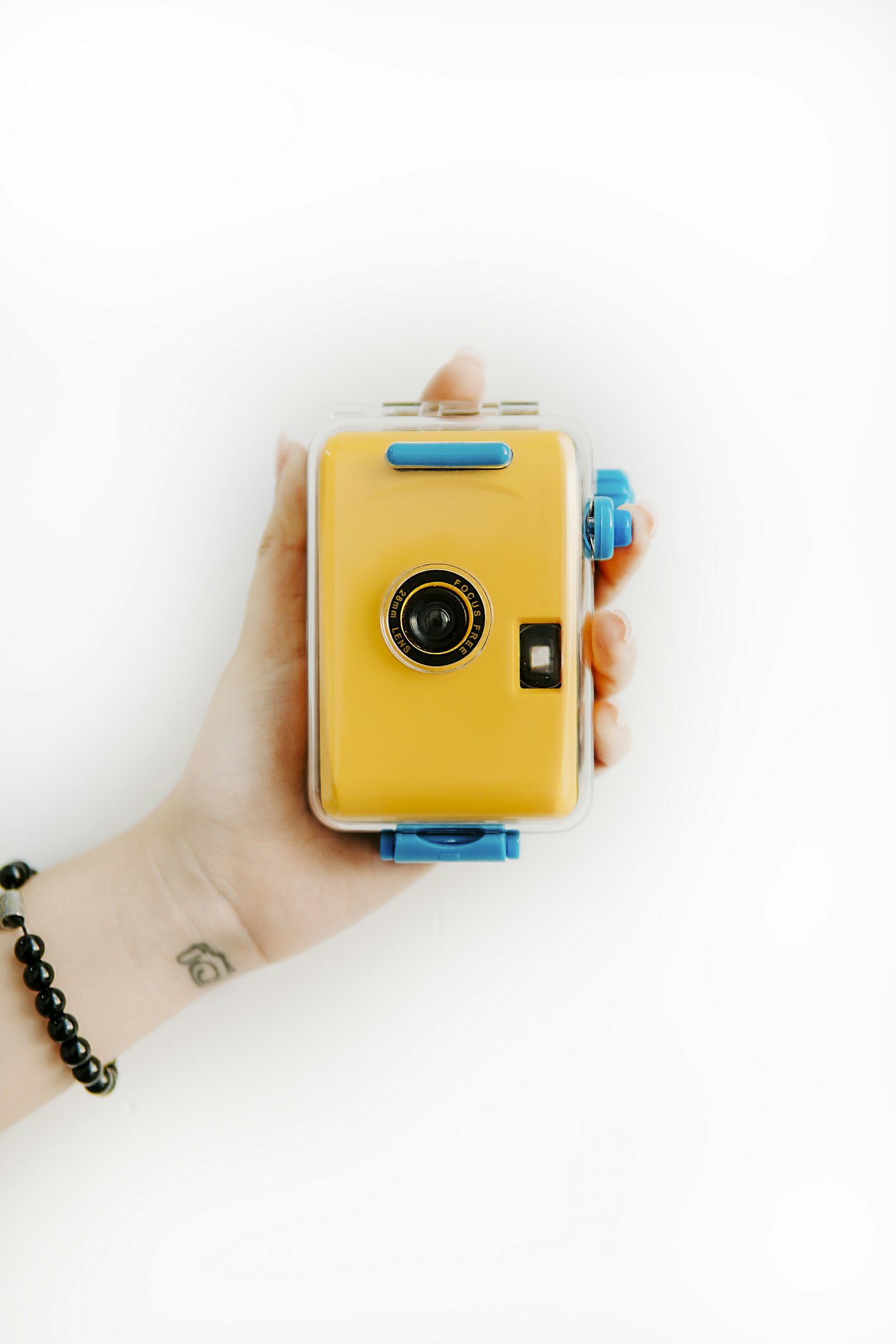 Hand holding a yellow toy camera