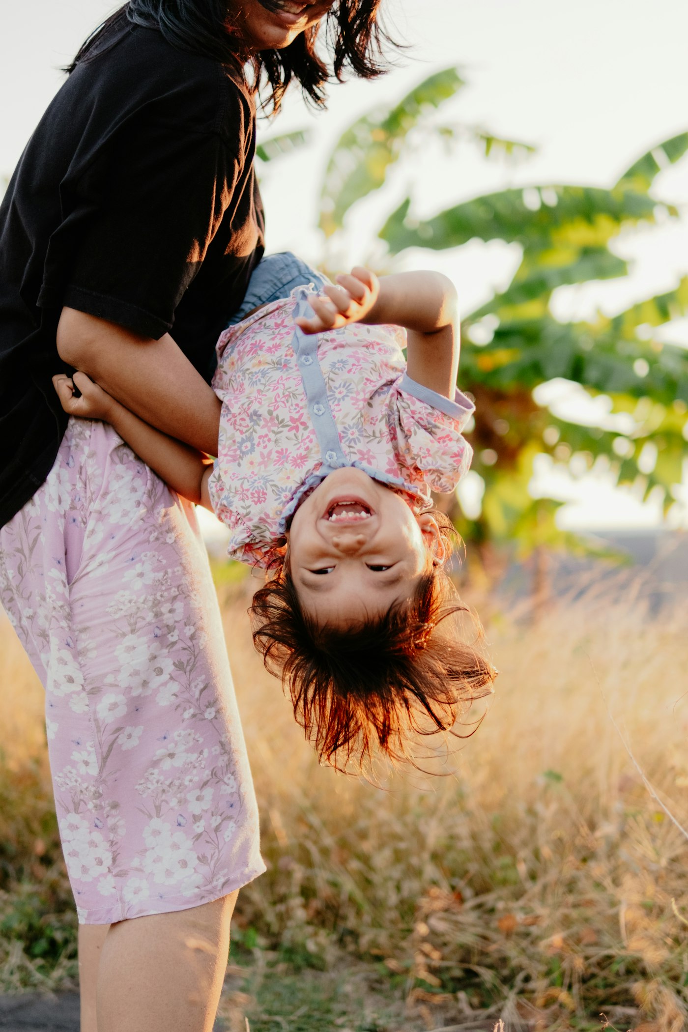 Parent swinging a laughing child upside down