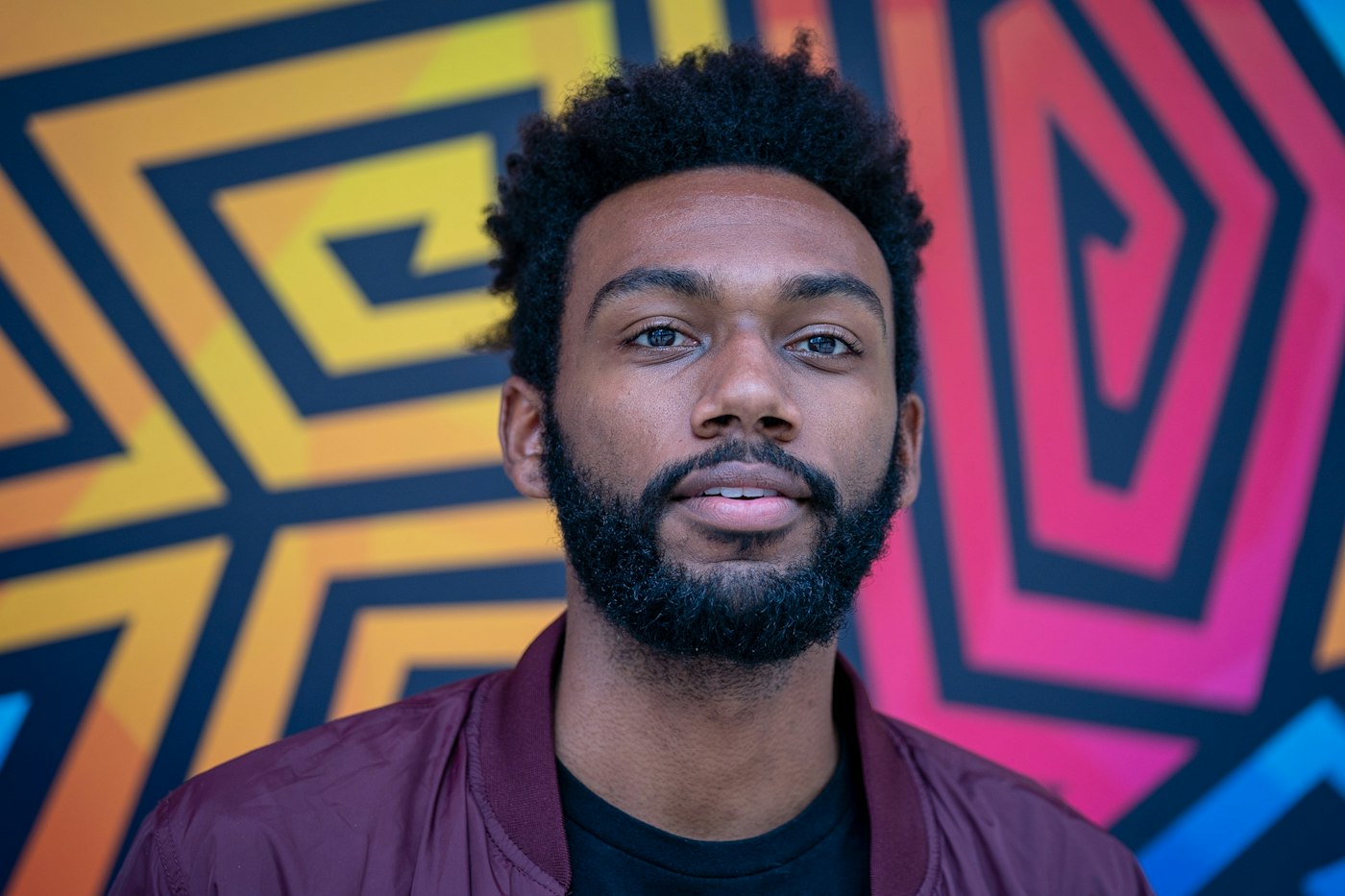 Portrait of a man in front of a bold geometric mural